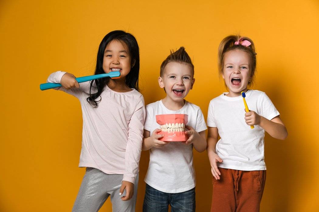 Kids smiling and holding toothbrushes