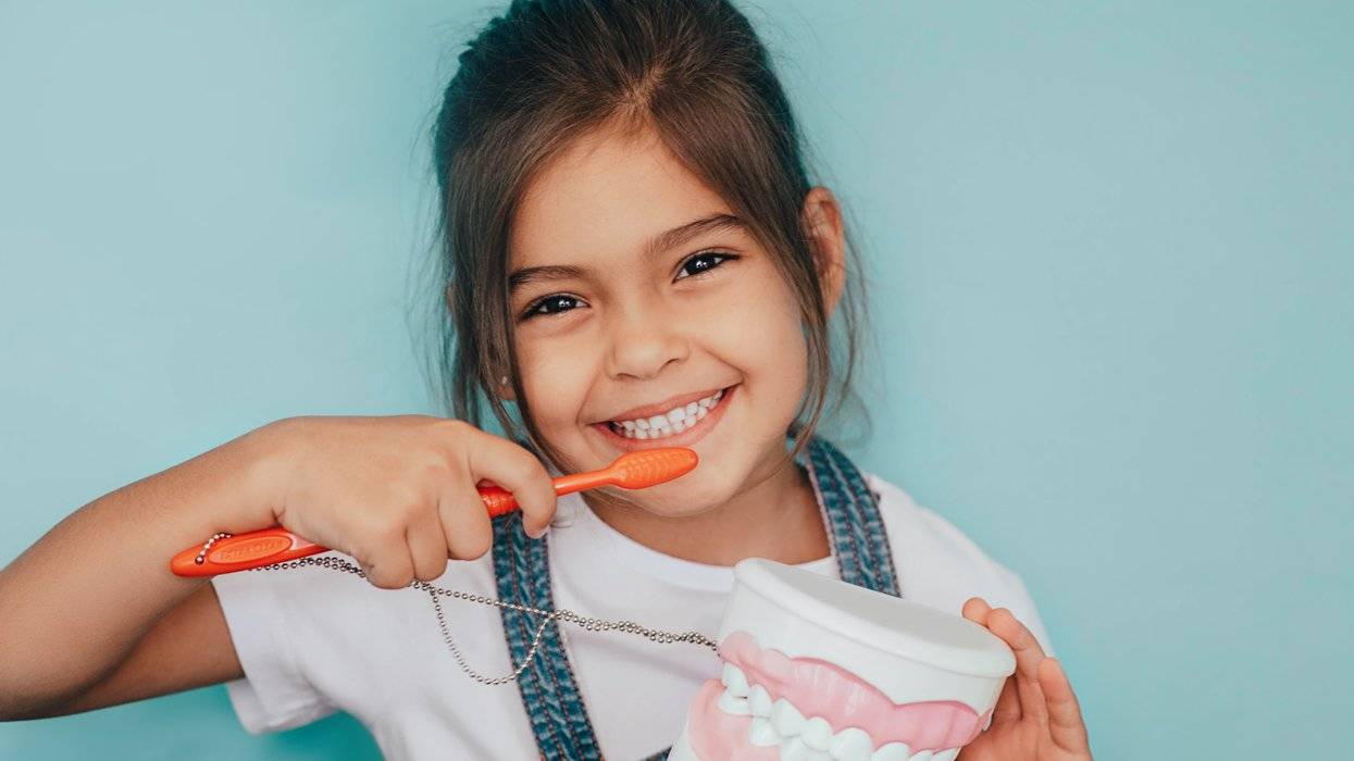 little girl smiling and holding toothbrush