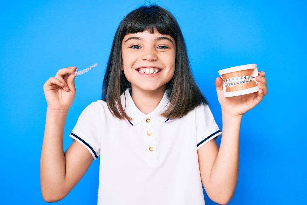 A picture of a kid showing two types of braces.